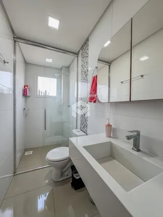 Foto de um banheiro moderno com box de vidro e bancada branca.