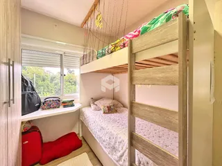 Quarto com cama de madeira e janela com vista para a vegetação externa.