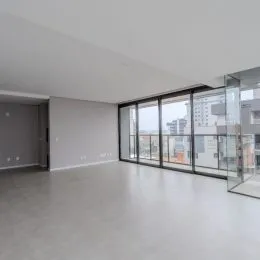 Foto de um ambiente interno amplo com piso cinza e grandes janelas de vidro.