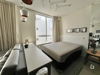 Quarto moderno com grande janela e cortinas claras.