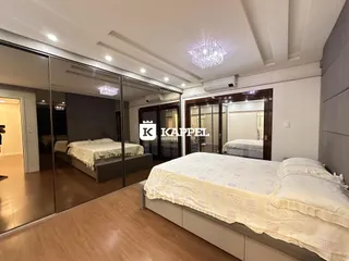 Quarto com cama de casal e piso de madeira clara.