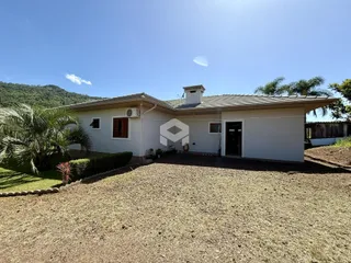 Fachada de uma casa em Lajeado, Brasil, com jardim gramado e terreno seco na frente.