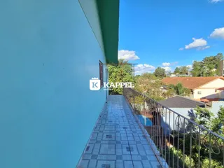 Vista da varanda com piso de azulejos e paisagem verde ao fundo.