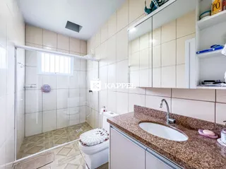 Foto de um banheiro com box de vidro e bancada de granito.