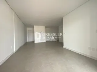 Ambiente interno de um espaço vazio com paredes brancas e piso cinza.