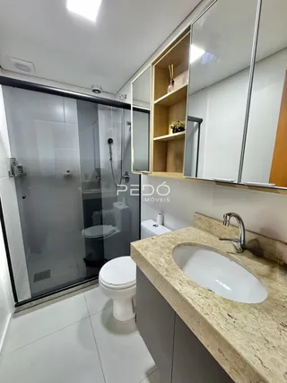 Banheiro moderno com box de vidro e bancada de granito.