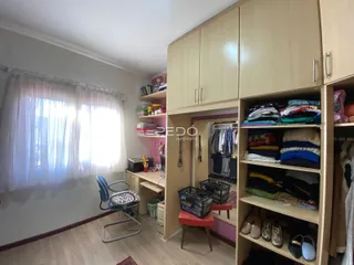 Quarto com grandes janelas e armários em madeira clara.