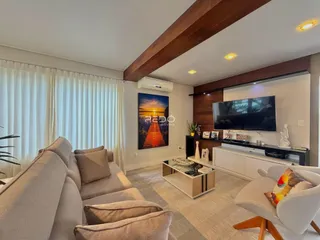 Sala de estar moderna com sofá e televisão em um ambiente bem iluminado.
