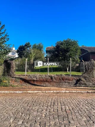 Vista externa de uma propriedade com cerca e vegetação no fundo.