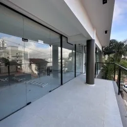 Varanda moderna com piso claro e grade de vidro.
