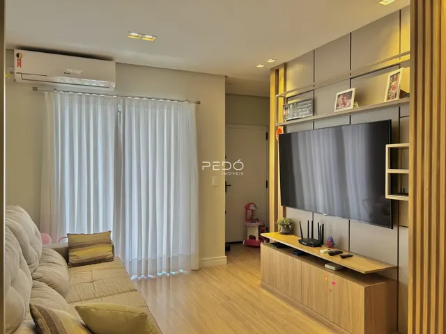 Sala de estar com sofá e televisão em um apartamento.