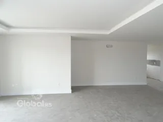 Imagem de um ambiente interno vazio com paredes brancas e piso claro.
