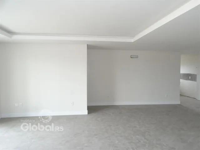 Imagem de um ambiente interno vazio com paredes brancas e piso claro.