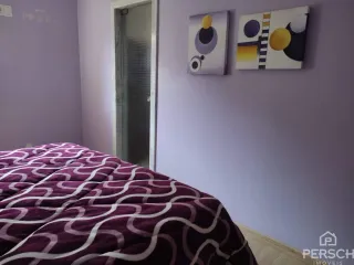 Quarto com cama e parede roxa em um imóvel.