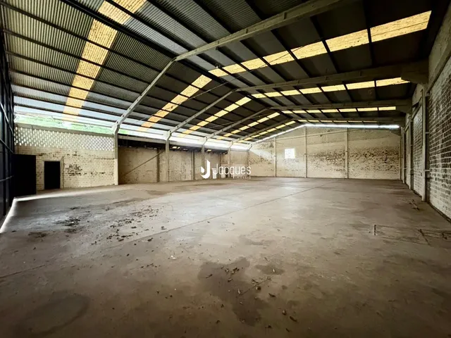 Espaço interno de um imóvel com estrutura de telhado metálico exposta.