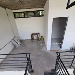 Hall de entrada com escadas e teto de madeira clara.