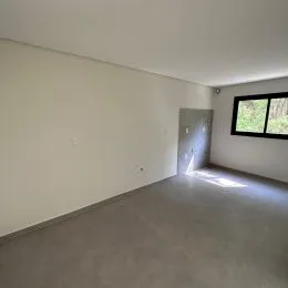 Vista interna de um corredor com paredes brancas e piso claro.