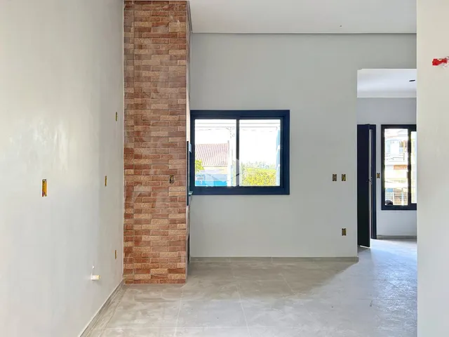 Hall de entrada com parede de tijolo aparente e piso de cerâmica.
