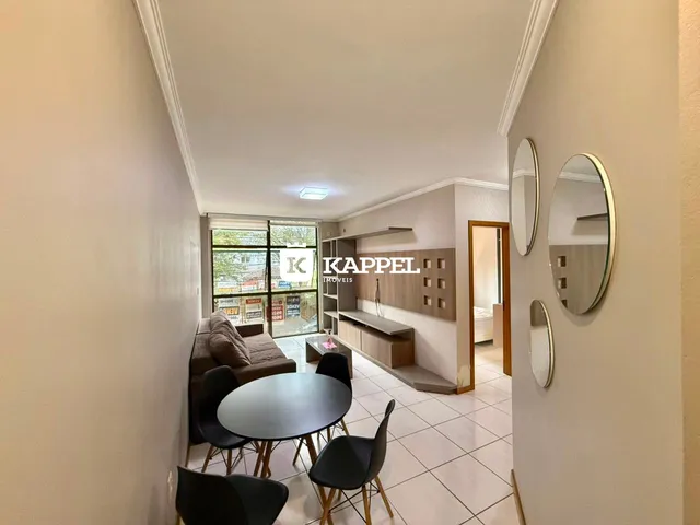 Uma sala de estar com mesa de jantar e janelas que dão vista para o exterior.