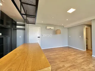 Ambiente interno de uma sala com piso de madeira e paredes cinzas.