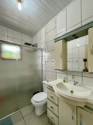 Foto de um banheiro com revestimento cerâmico e louças brancas.