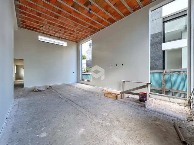 Imagem de um espaço interno em construção com piso de concreto e teto de tijolos exposto.