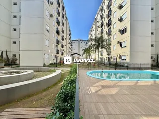 Vista externa de um complexo residencial com piscina e paisagismo.