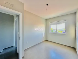 Interior de um corredor com piso de cerâmica e paredes claras.