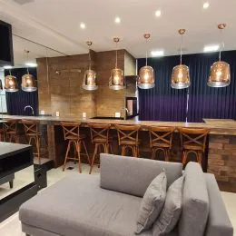 Foto interna de uma sala de estar com sofá e painel de madeira.