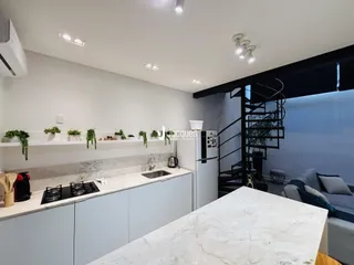 Vista da cozinha moderna com bancadas de mármore branco e armários brancos.