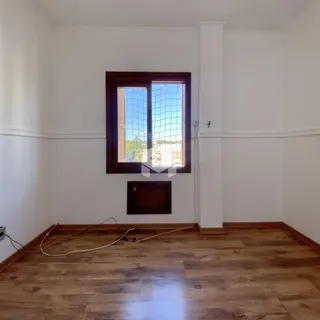 Foto de uma sala com piso de madeira e parede branca em um imóvel.