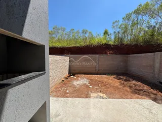 Vista externa mostrando um muro de contenção de concreto e terra no quintal da propriedade.