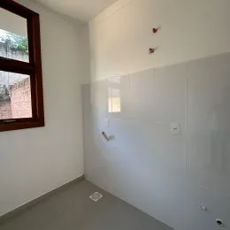 Vista interna de um cômodo com parede branca e janela.