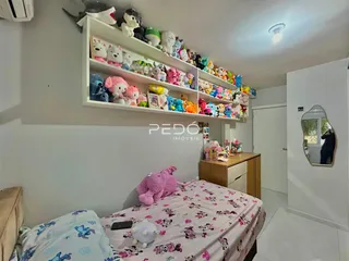 Quarto com cabeceira decorada com prateleiras de bichos de pelúcia e cama florida.