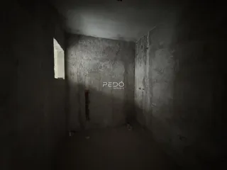 Corredor interno de um imóvel com paredes de concreto aparente.
