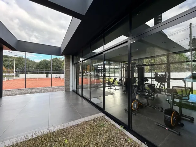 Ambiente interno moderno com grandes painéis de vidro e estrutura preta.