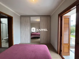 Vista interna de um quarto com cama rosa e painéis de armário.
