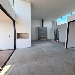 Espaço interno amplo com paredes brancas e piso de concreto aparente.