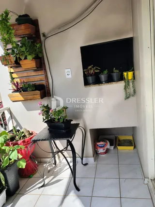 Parede interna com prateleiras de plantas e um suporte de metal na sala.