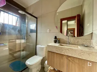 Foto de um banheiro com box de vidro e louças brancas.