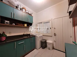 Vista interna de uma cozinha com armários verdes e bancada.
