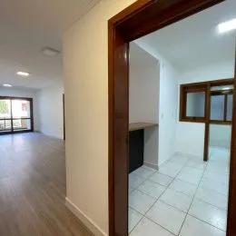 Corredor interno com paredes claras e piso de madeira.