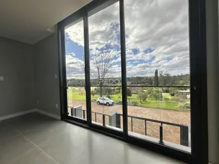 Uma sala de estar com grandes janelas que oferecem uma vista para um campo aberto.