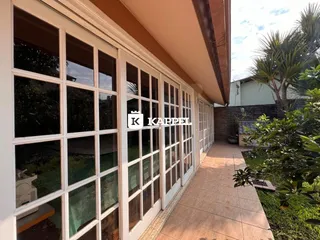 Fachada de uma residência com grandes janelas de vidro e um caminho de acesso.