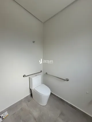 Foto de um banheiro interno com vaso sanitário e barras de apoio.