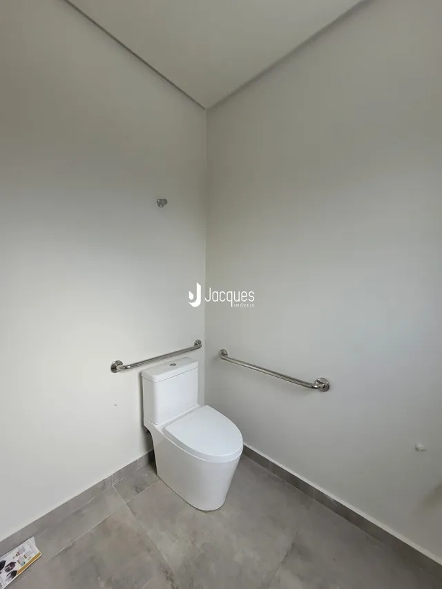 Foto de um banheiro interno com vaso sanitário e barras de apoio.