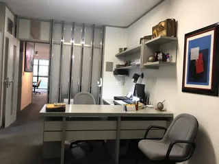 Imagem de uma sala de estar com paredes brancas e estantes de madeira.