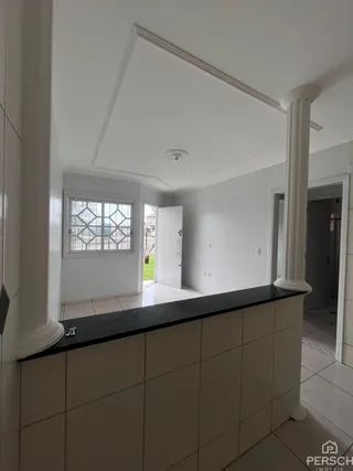 Vista de um corredor com colunas brancas e bancada escura.