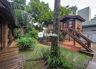 Área externa com gramado e deck de madeira adjacente à residência.