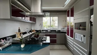 Cozinha moderna com armários escuros e ilha azul em um imóvel no Brasil.